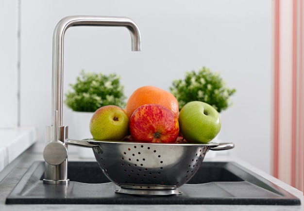 Frutta nella tazza sul lavello della cucina vicino al rubinetto dell'acqua.