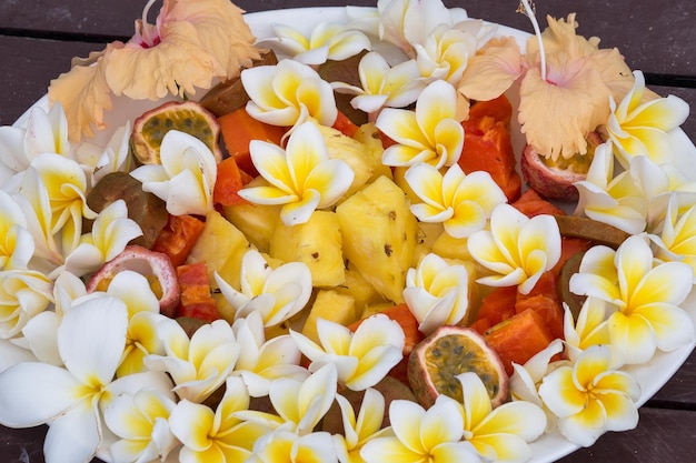 写真 プレートにパイナップル パパイヤ パッション フルーツと白いフランジパニの花を添えたフルーツ デザート サラダ