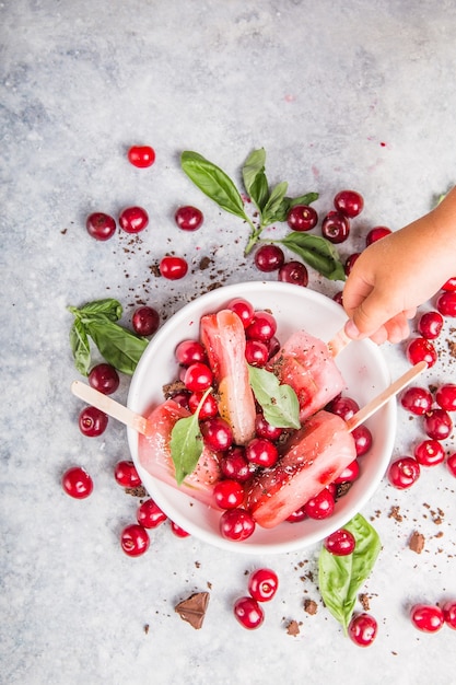 Fruit en bessenijslollys met kersen in een kom