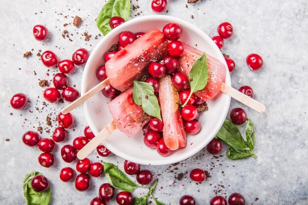 Fruit en bessenijslollys met kersen in een kom