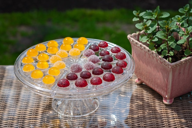 Fruit- en bessenmarmeladesnoepjes, geleisnoepjes op een transparante glazen gebakstandaard met munt in een pot.