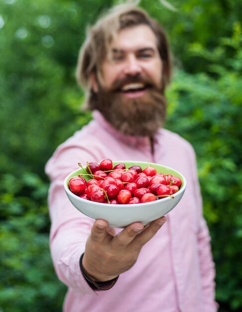 Fruit full of vitamins. healthy food and eating. dieting concept. mature brutal hipster with red berry bowl. natural and organic. happy bearded man holding cherry. summer harvest. for you.