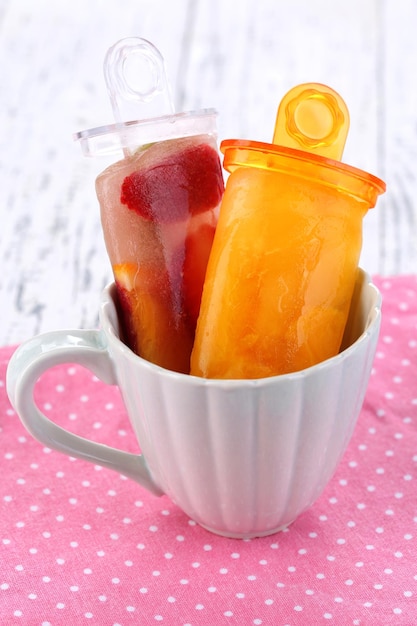 Fruit ice cream in cup on wooden table closeup