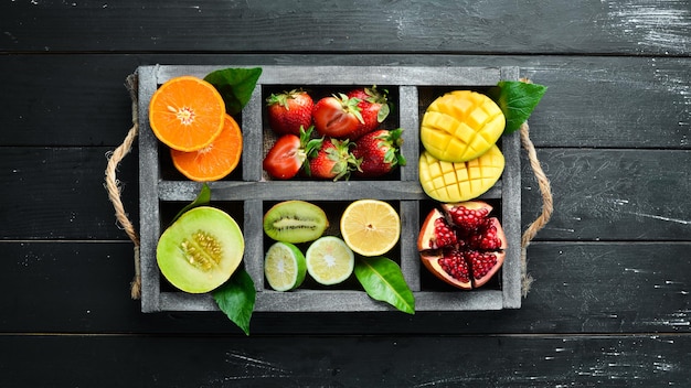 Fruit in een houten kist. Citrus, meloen, granaatappel, aardbei, banaan. Bovenaanzicht. Vrije ruimte voor uw tekst.