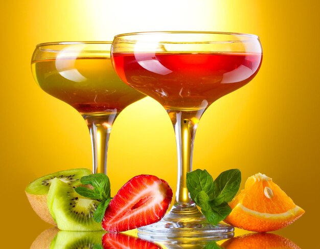 Fruit jelly in glasses and fruits on yellow background