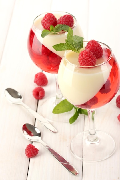 Fruit jelly with raspberries in glasses on wooden table