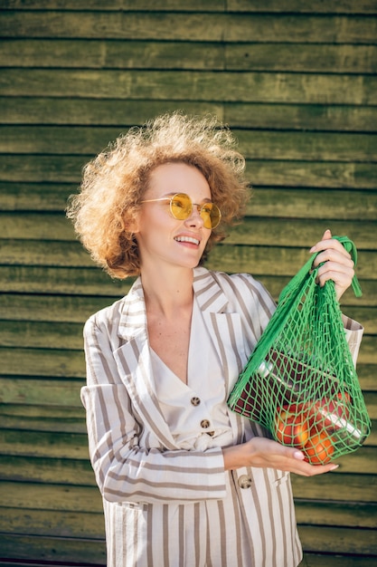 Fruit. Jonge vrouw in zonnebril met een netje met fruit