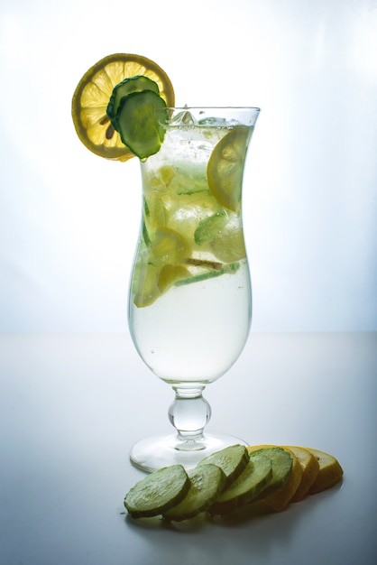 Fruit lemonade in hurricane glass with lemon and cucumber.