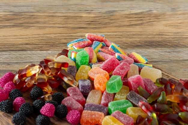 Foto dolci alla marmellata di frutta, caramelle di gelatina su una scrivania in legno. dessert naturale di frutta con zucchero.