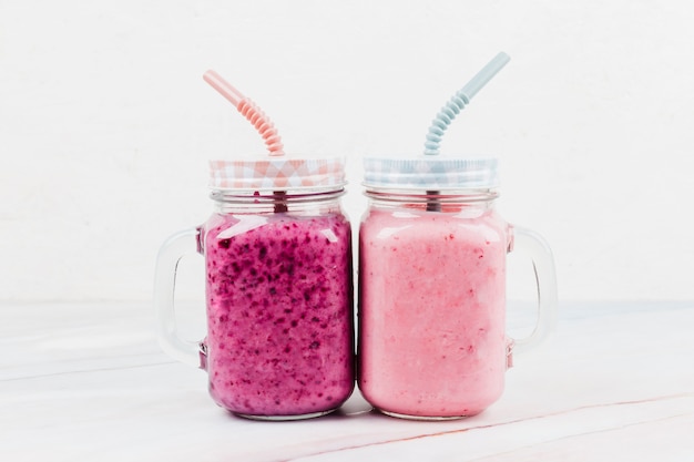 Photo fruit milk cocktail in drinking jars with straws