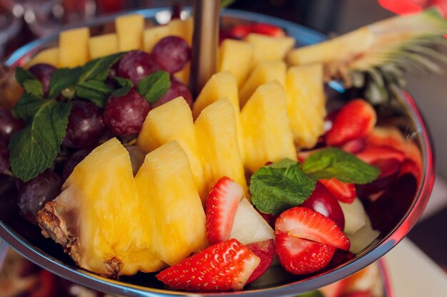 Fruit mix Perzik druiven appel watermeloen meloen framboos pruim Stukjes fruit op een bord liggen op een witte houten achtergrond Kopieer ruimte ruimte voor tekst