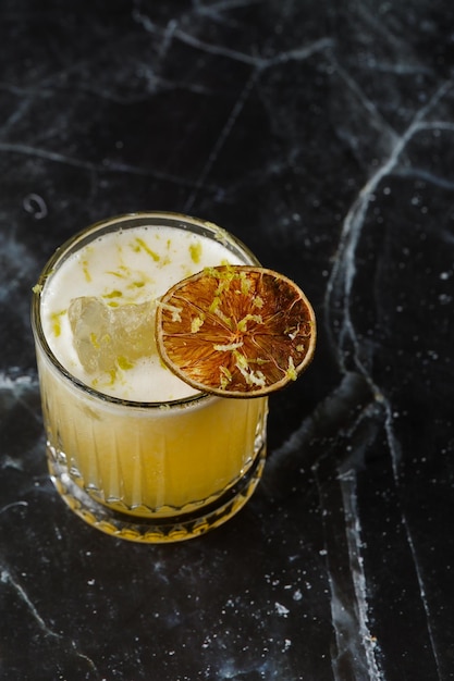 Fruit mixology with mezcal and dry lime on black marble background Warm colored cocktails Mezcal cocktail