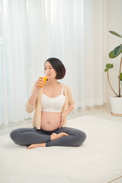 임신 한 여자의 손에 과일과 오렌지 주스.