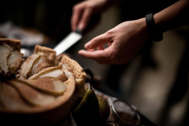 Fruit pie crust. Chef's hand cut with knife pie crust sliced on a rustic kitchen table.