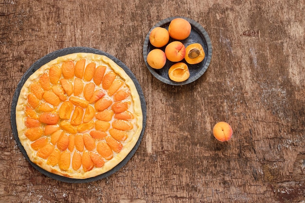 Fruit pizza with peaches on a wooden dark table homemade summer vegetarian pie top view