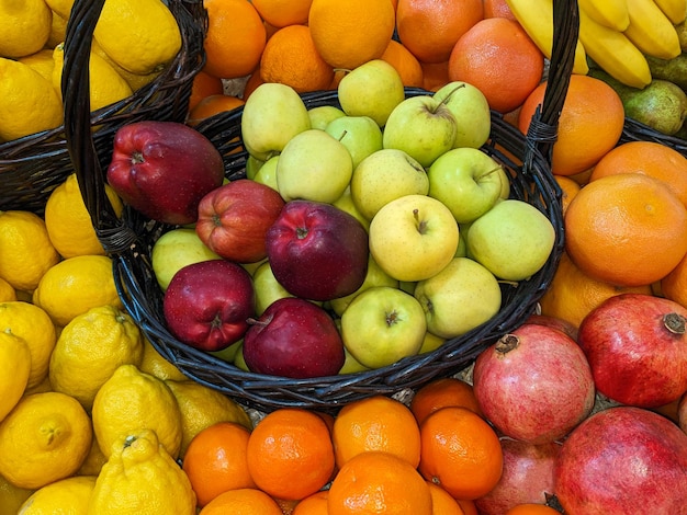 Fruit platter green and red apples in a basket among lemons tangerines and pomegranates