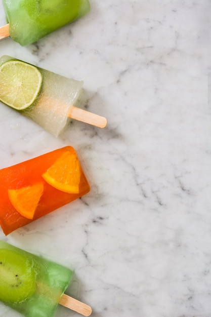 Fruit popsicles on white marble 