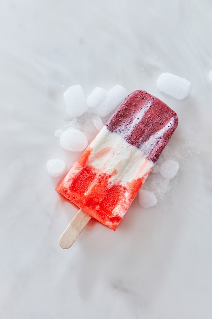 Fruit red ice cream popsicles on a stick with ice