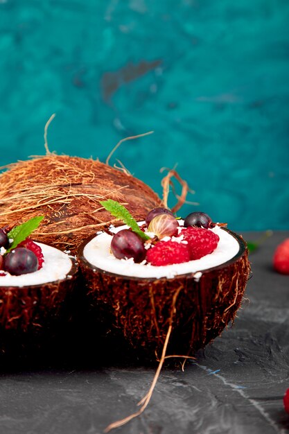 Fruit salad agrus, gooseberry, rasbberry in coconut shell bowl