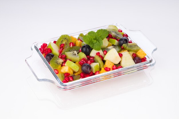 Fruit Salad arranged in a transparent glass container with white background.