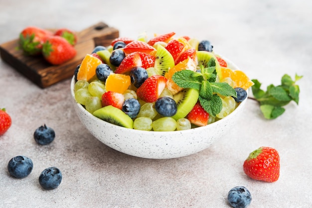 Fruit salad of blueberries, strawberries, grapes and kiwi in a plate, selective focus