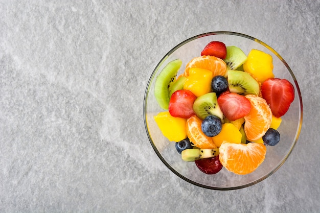 Fruit salad in crystal bowl on gray top view with copy space