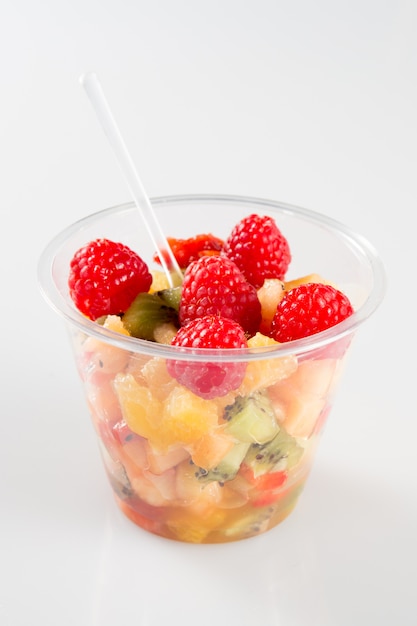 A fruit salad in take away clear plastic cup on white background