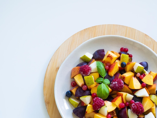 Fruit salad with fresh plum peach nectarine pear and frozen raspberries