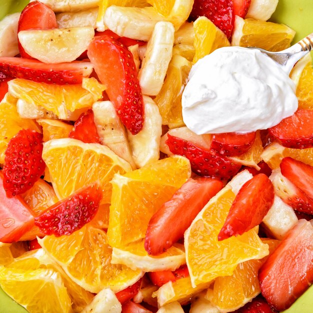 Fruit salad with strawberries oranges bananas and sour cream