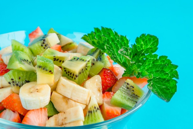 Fruit salad with strawberry kiwi orange and lemon on wooden background Top view with copy space