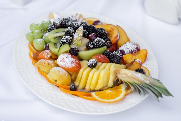 Фото Нарезанные фрукты на белой тарелке, посыпанной сахарной пудрой