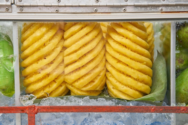 Фото Фрукты, такие как ананас, манго находятся в стеклянном шкафу на мобильных транспортных средствах для продажи.
