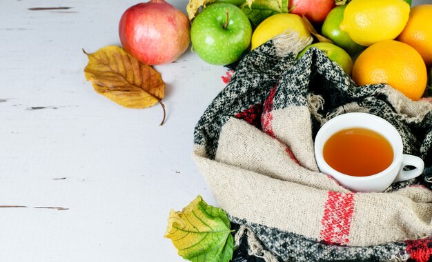 Fruit tea cup, warm scarf, citrus tropical fruits as symbols of antiviruses remedy, booster immune system