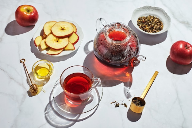 Foto tè alla frutta con mele e timo e miele in teiera e tazza di vetro