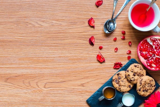 Tè alla frutta con limone, latte, miele, arancia, melograno, su uno sfondo di legno