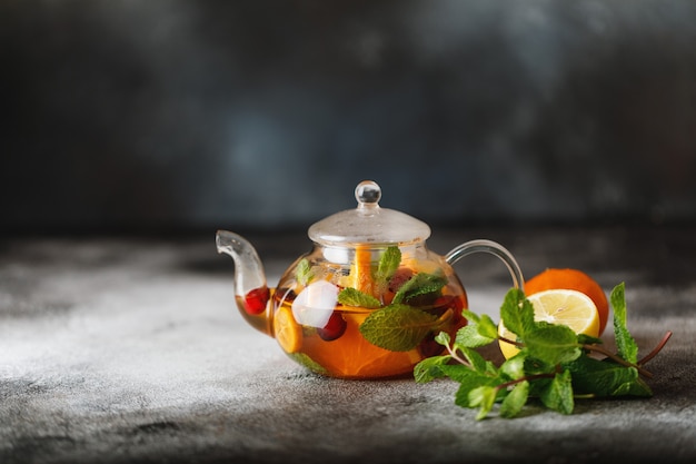 Fruit tea with mint, oranges and cranberry on dark stone background. A cup of hot tea