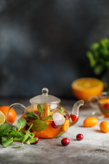 Fruit tea with mint, oranges and cranberry on dark stone background. A cup of hot tea