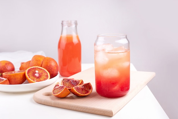 Fruit water in a glass with ice cubes, red orange lemonade, summer refreshing drink