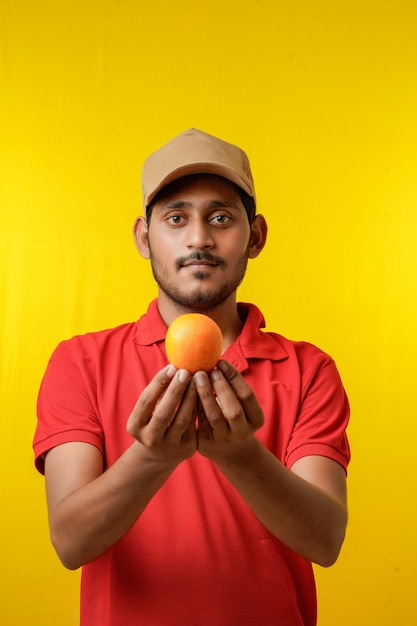 Fruitbezorgingsconcept: indiase bezorger die oranje fruit in de hand houdt