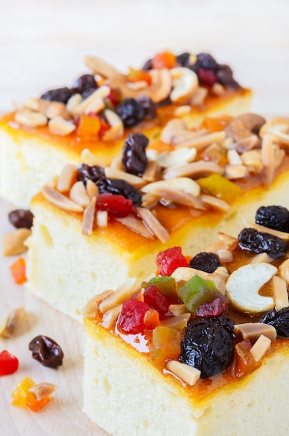 Fruitcake topped with mix fruits and Cashew nuts on wooden cutting board