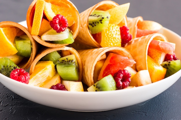 Fruitdessert. wafel kegels met rijp gehakt fruit op een bord. gezond eten.