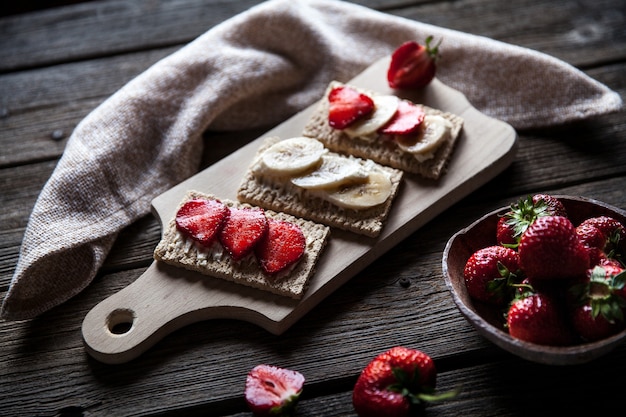 Fruitige toast op houten tafel. Aardbeien, brood, boter en kaas.Vintage stijl en