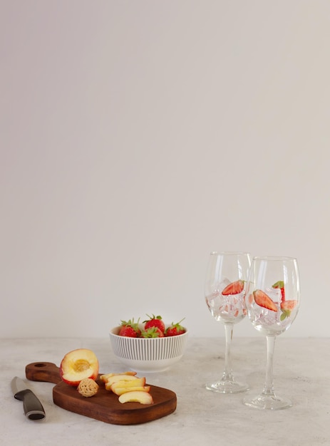 Foto fruitingrediënten voor het bereiden van limonade coctail sangria glazen met ijs op de grijze achtergrond met kopieerruimte