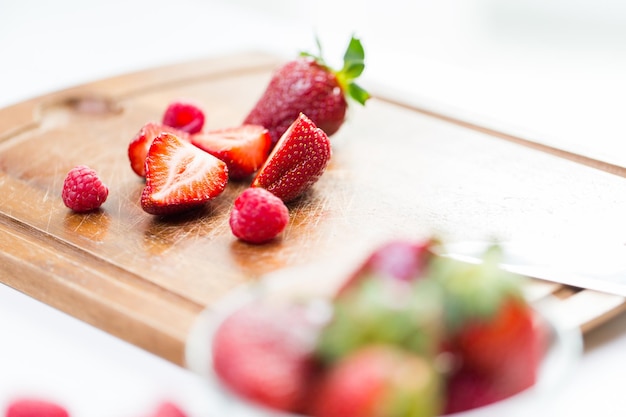 fruits, berries, diet, eco food and objects concept - close up of fresh ripe red strawberries on cutting board