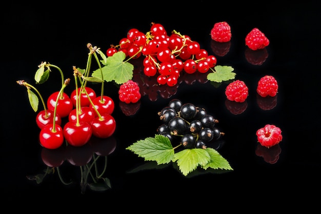 Fruits of cherry, raspberry, black currant and red currant on a dark background.