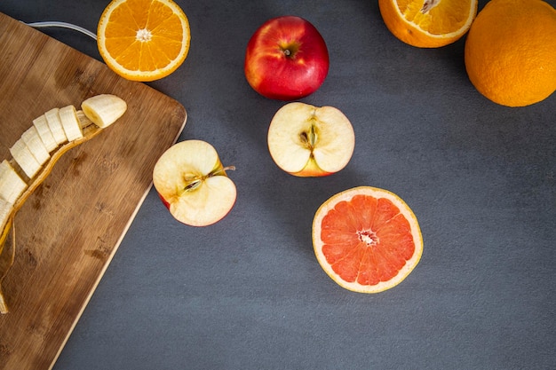 Frutta tagliata a metà su una tavola di legno su sfondo grigio vista dall'alto piatto