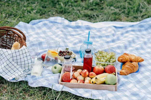 Foto frutta e bevande sulla tovaglia al picnic estivo in vacanza in famiglia in natura