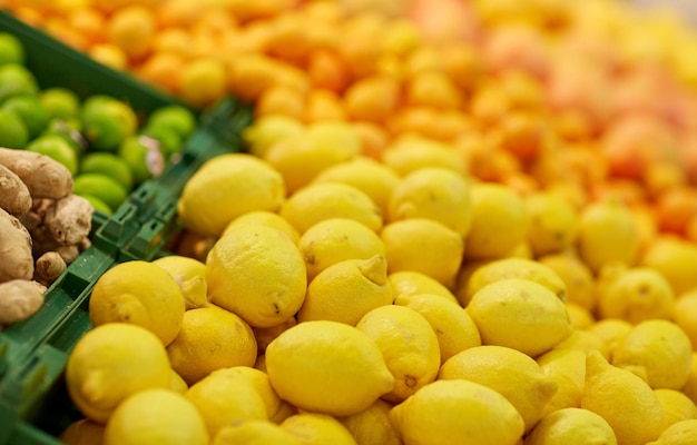 фрукты, урожай, продукты питания и концепция продажи - лимоны в продуктовом магазине или на рынке