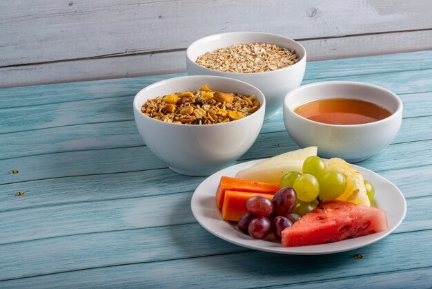 Fruits honey oats and granola on blue wooden table Healthy food