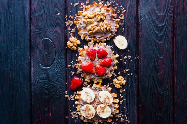 Fruits and nuts in chocolate paste on waffle on a black background